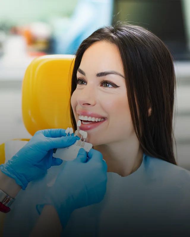 A woman smiling while a dentist reviews whitening options